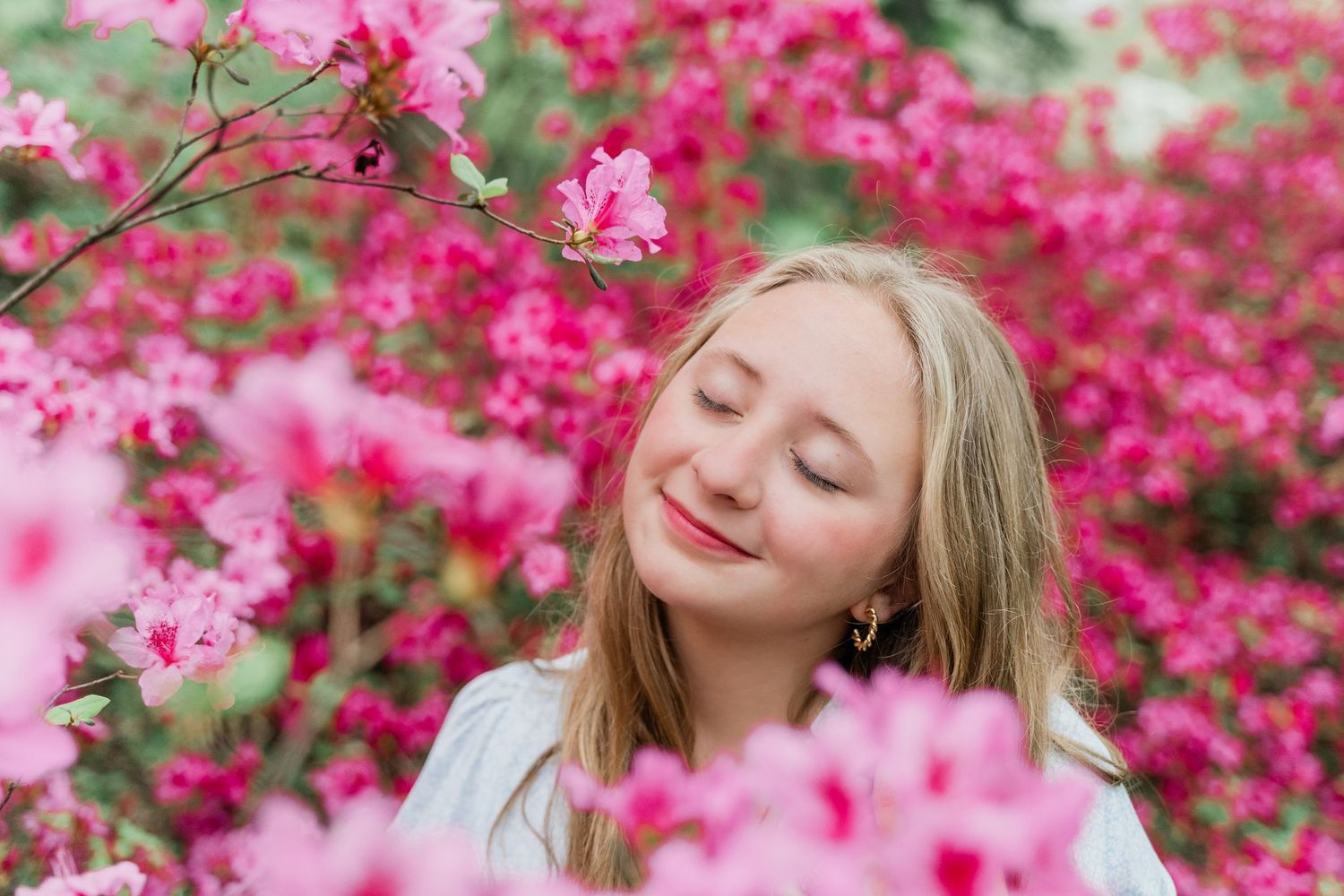 A Maumee High School senior poses in peaceful spring scene with bright pink azalea blossoms and blooming flowers at Toledo Botanical Garden.