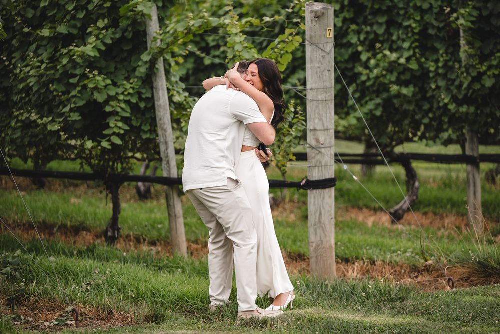 A couple embracing in celebration among vineyard rows on a summer day.
