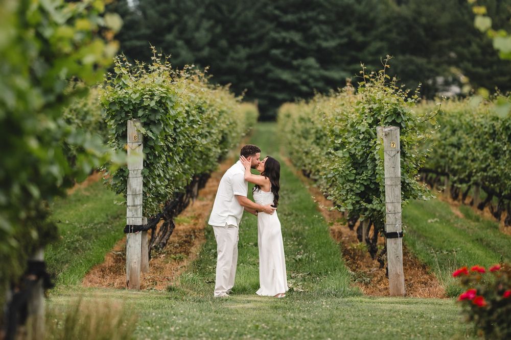 A romantic moment between a couple standing in a picturesque vineyard pathway.
