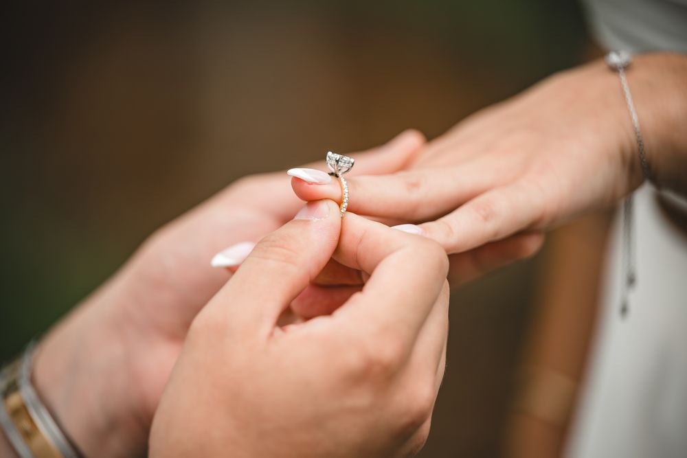 Close-up shots of an engagement ring being placed on a finger during a proposal.
