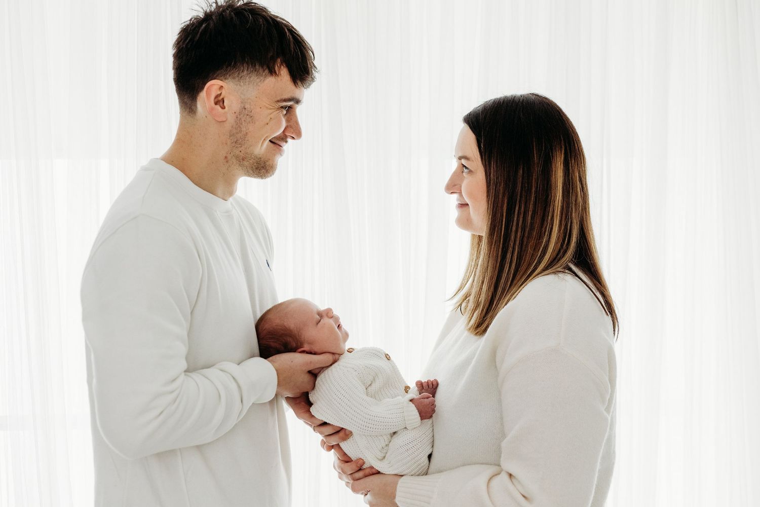 Baby peacefully asleep in white swaddle, photographed by Nottingham newborn photographer at Mapperley studio.