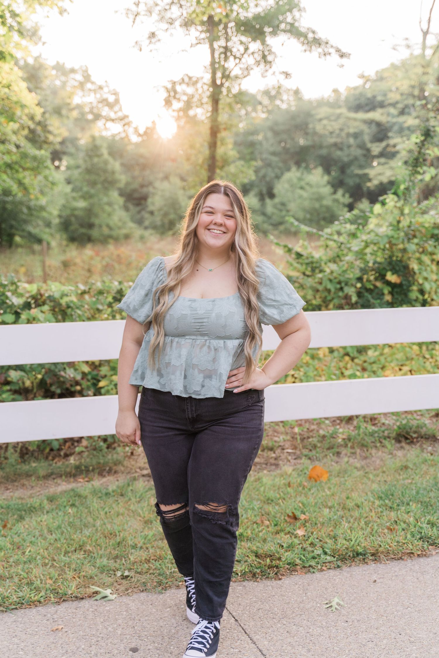Lake High School senior wearing a ruffled sage green top and distressed black jeans poses at Wildwood Metropark for photo session.