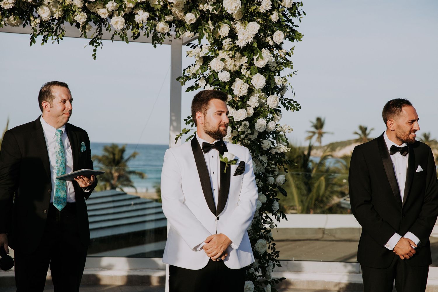 Wedding ceremony space decorated with lush white floral arrangements and greenery on rooftop venue.