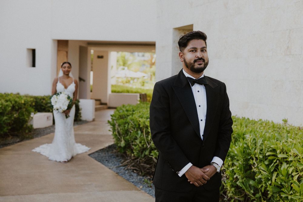 First look wedding moment at a tropical resort with white stucco walls and landscaping.