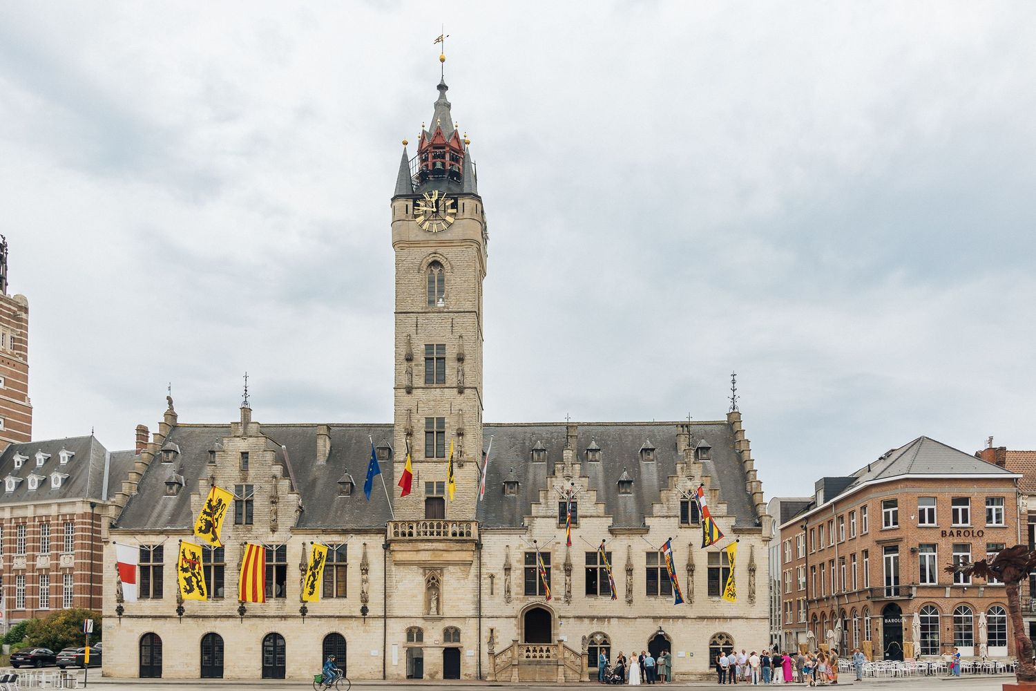 Historic Gothic style building facade with ornate architecture and clock tower in cloudy weather.