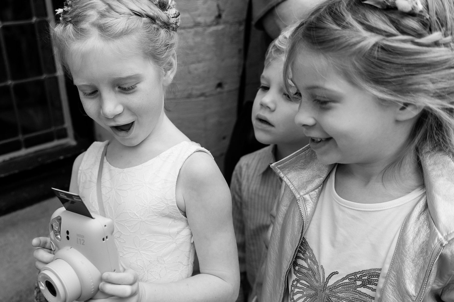 Black and white image of children in white dresses during formal event.