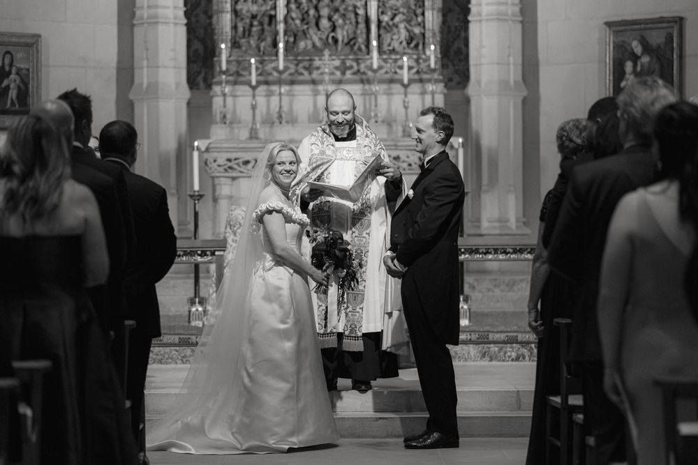 A wedding ceremony takes place in a grand church with guests watching from the pews.