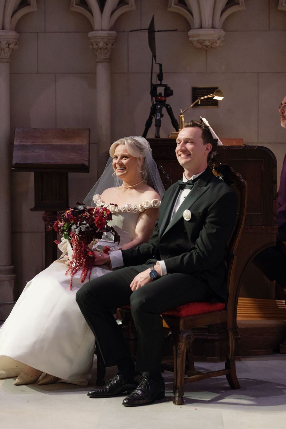 Wedding couple relaxing on wooden benches in an elegant church interior.