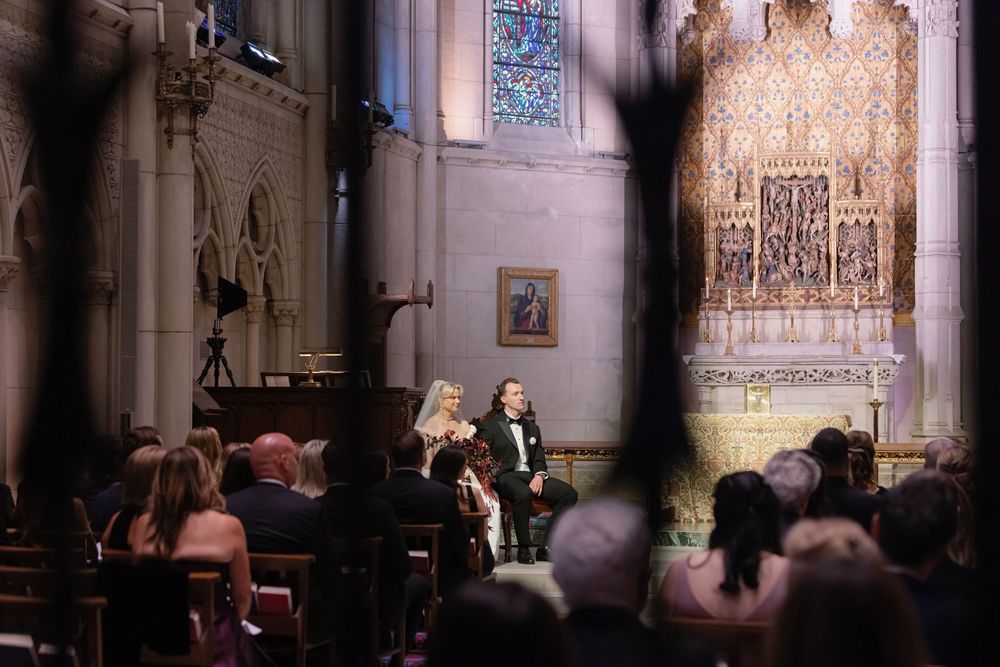 A traditional church wedding ceremony takes place in an ornate cathedral with guests seated in wooden pews.