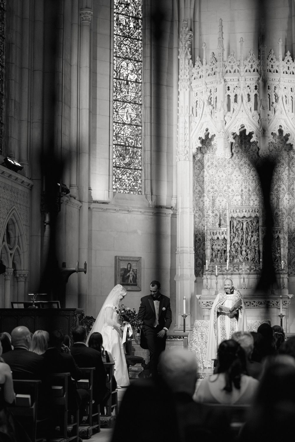 Traditional church wedding ceremony in a gothic cathedral with ornate stained glass windows and architectural details.