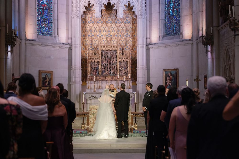 Wide panoramic view of a church interior during a wedding ceremony with stained glass windows.