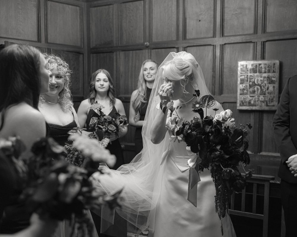 Black and white candid photo showing bridal party preparations and celebrations in an elegant wood-paneled room.