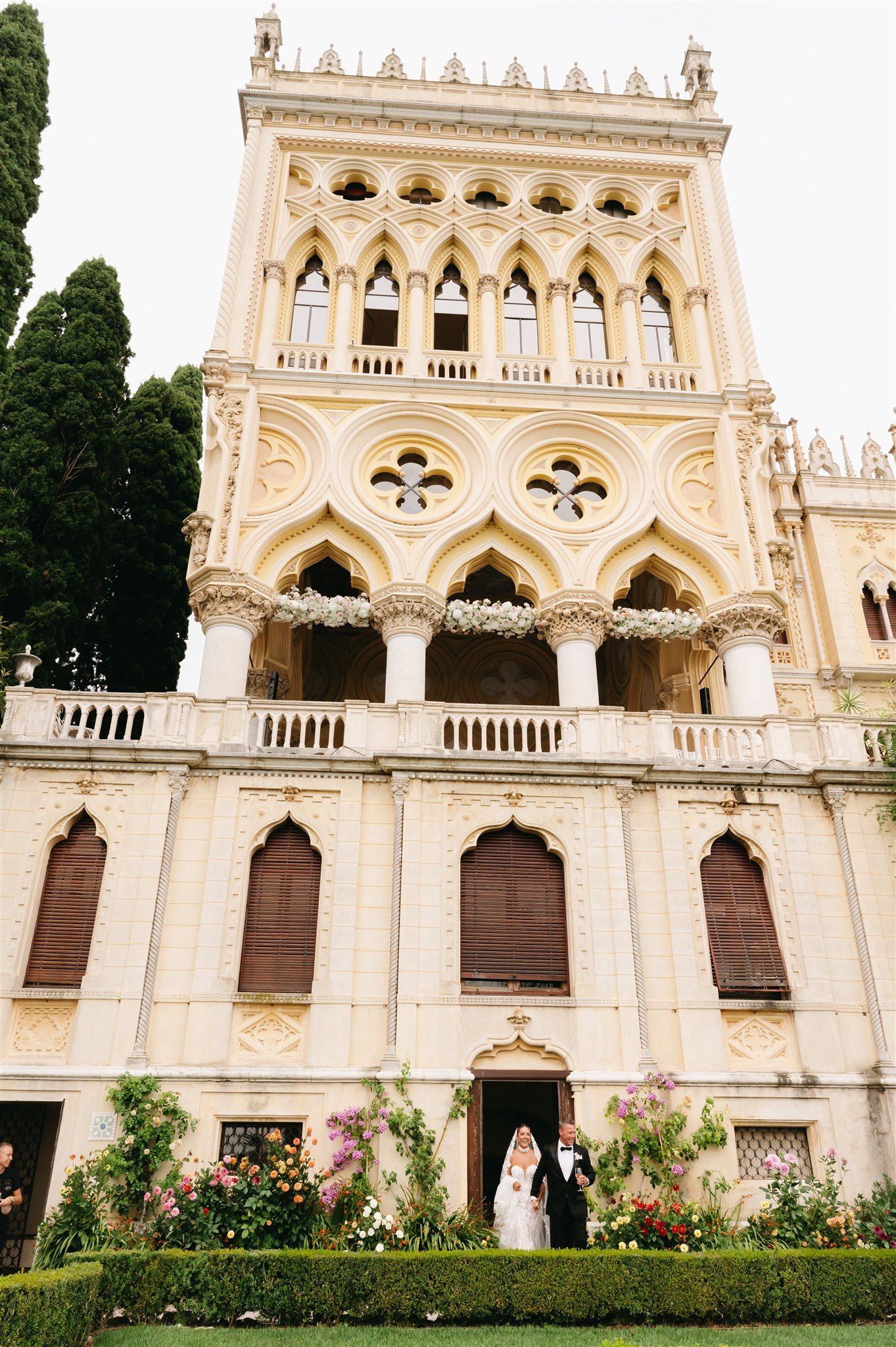 Gothic-style villa with ornate architectural details and manicured gardens in the foreground.