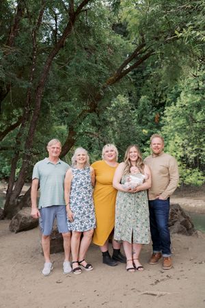 A group stands together posing for a portrait in a wooded outdoor setting on a sandy path.