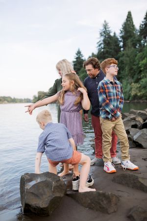 A group sits together on coastal rocks at the beach, enjoying the waterfront view at sunset.