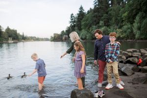 Five waterfront photos show people exploring a rocky shore near a lake or river at sunset.