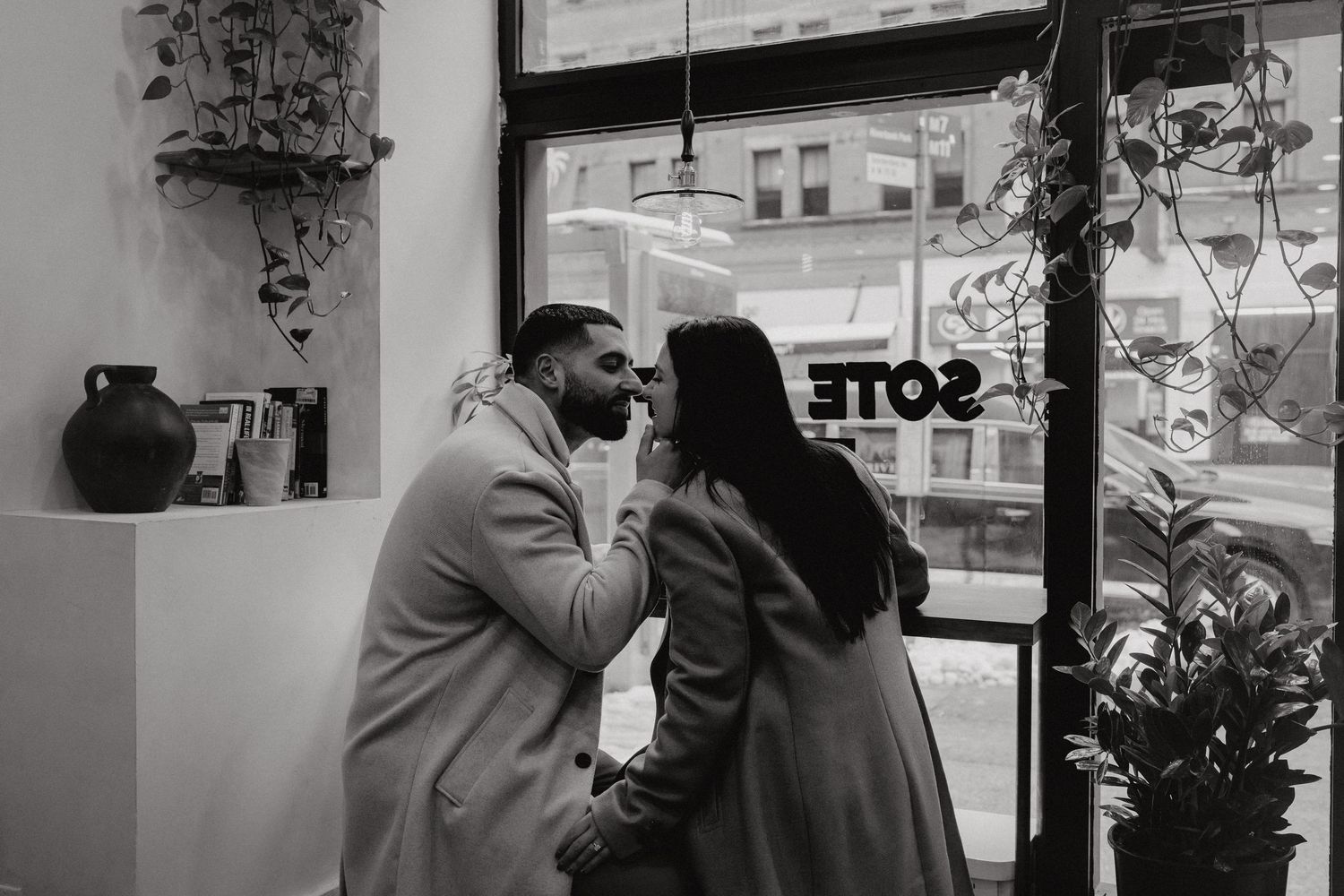 A couple sharing an intimate moment in a cozy cafe setting with window light.