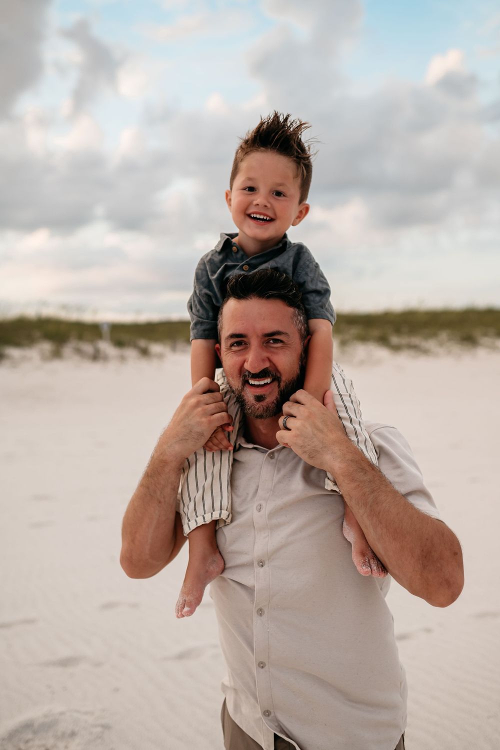 A playful piggyback ride moment between father and child on a sunny beach.