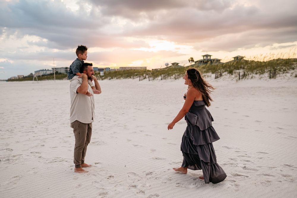 A family enjoys playful moments together during sunset on a white sandy beach.