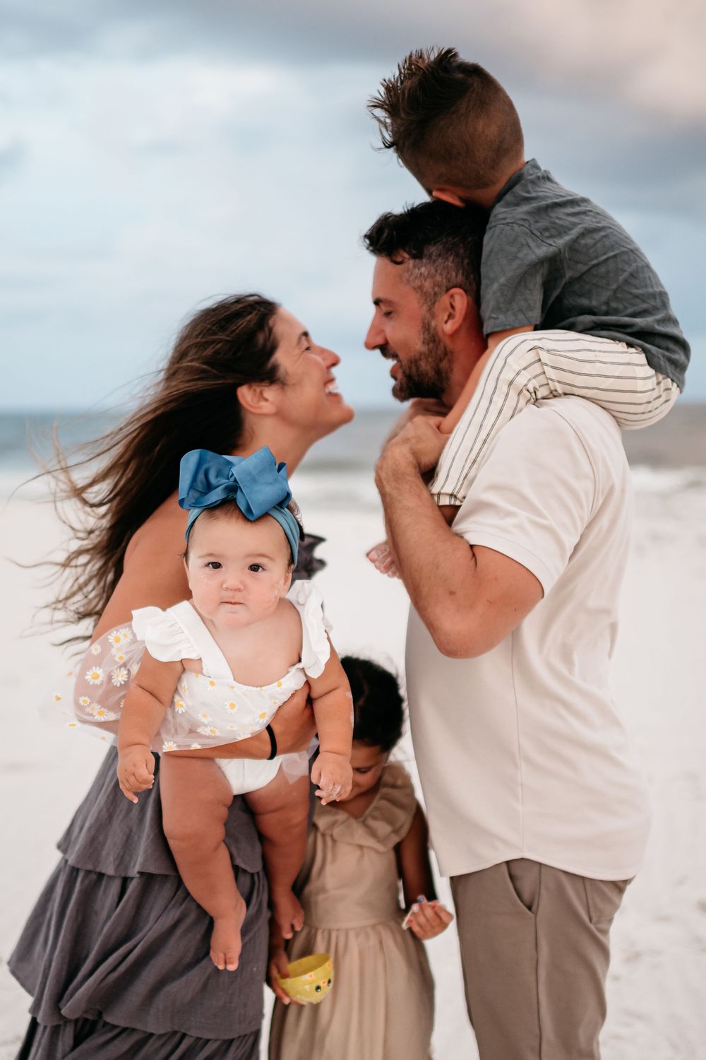 A loving family shares an intimate moment together on a beach at sunset.