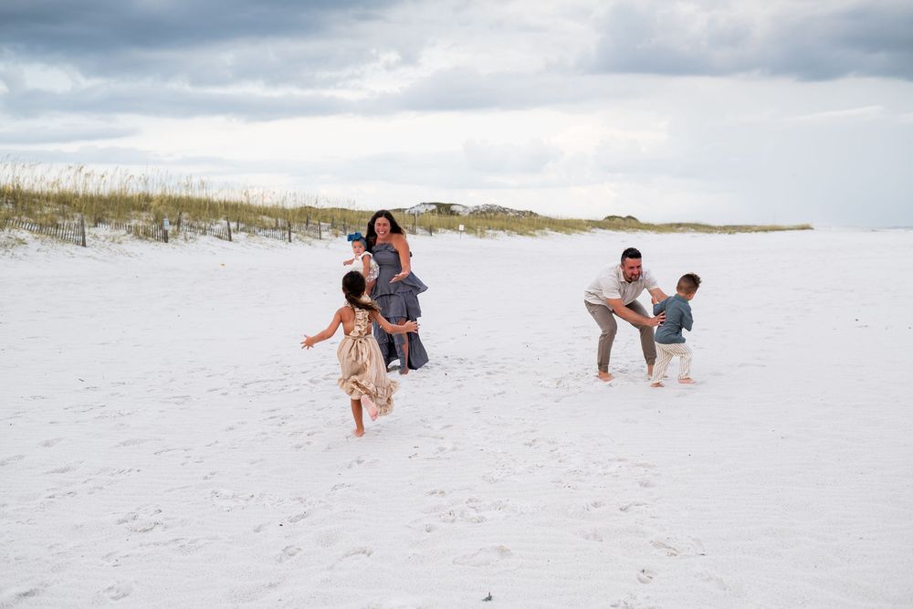 A joyful scene of people playing and walking on a white sandy beach under cloudy skies.