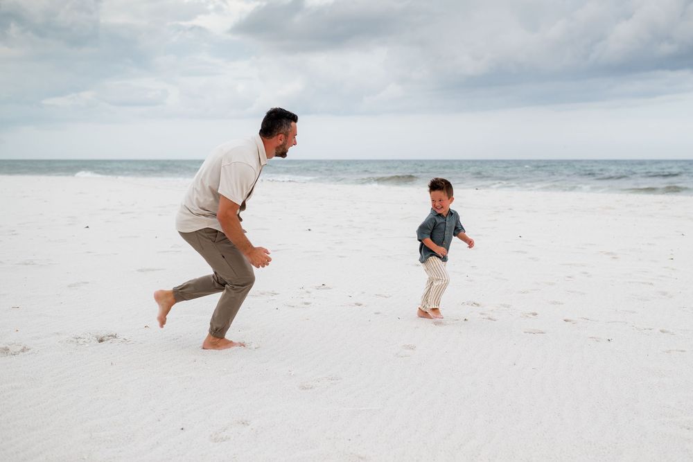 People running and playing together on a pristine white sand beach with ocean waves in the background.