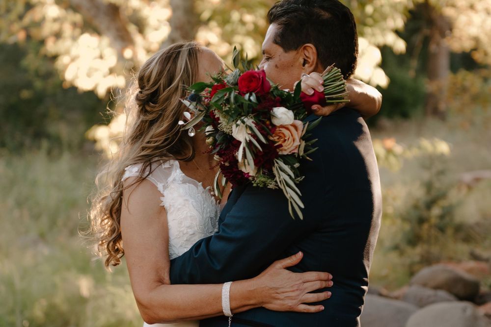 A romantic couple shares tender embraces and kisses in a golden-lit outdoor setting with natural scenery.