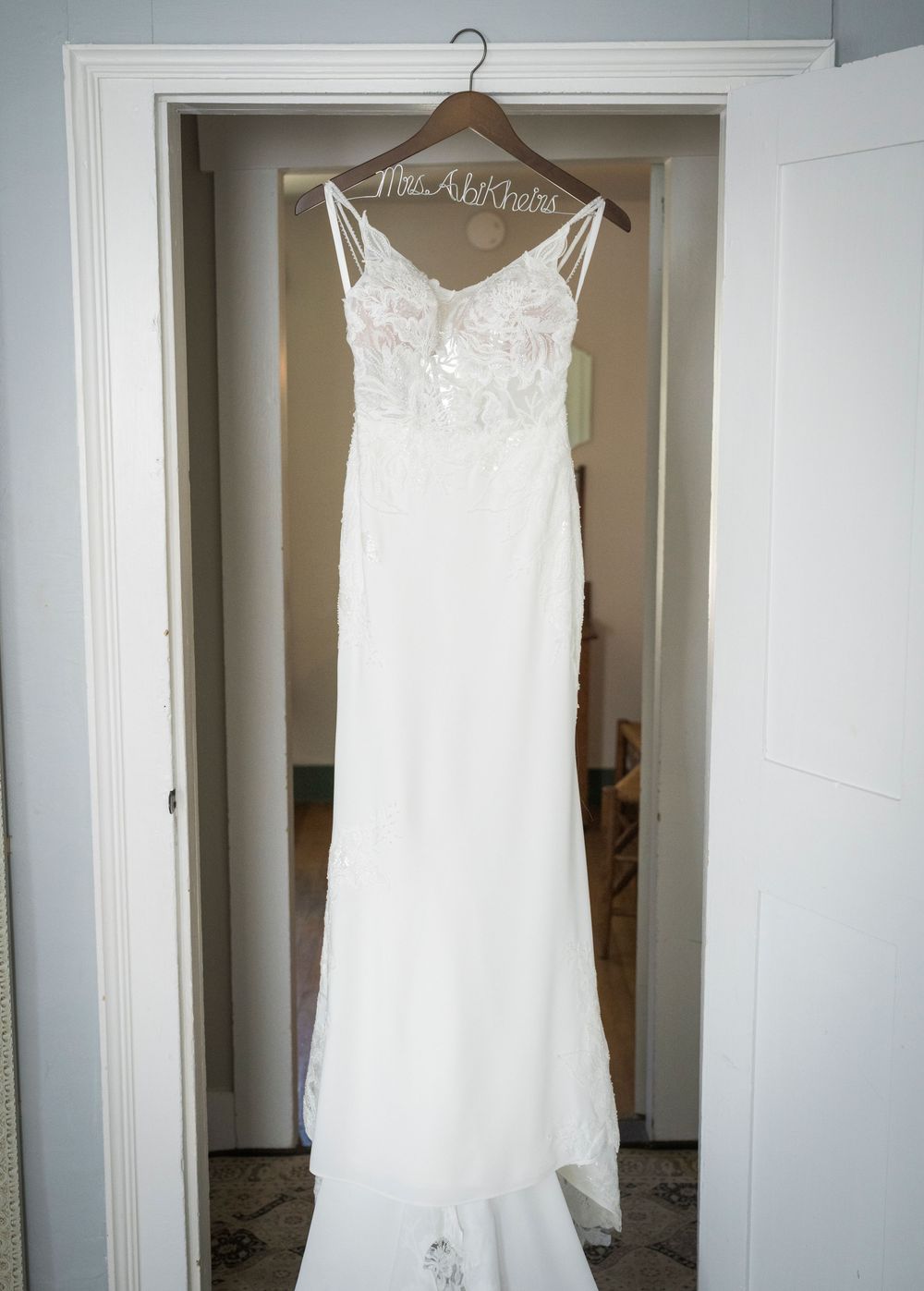 White wedding dress hanging on display in a bright, minimalist room.