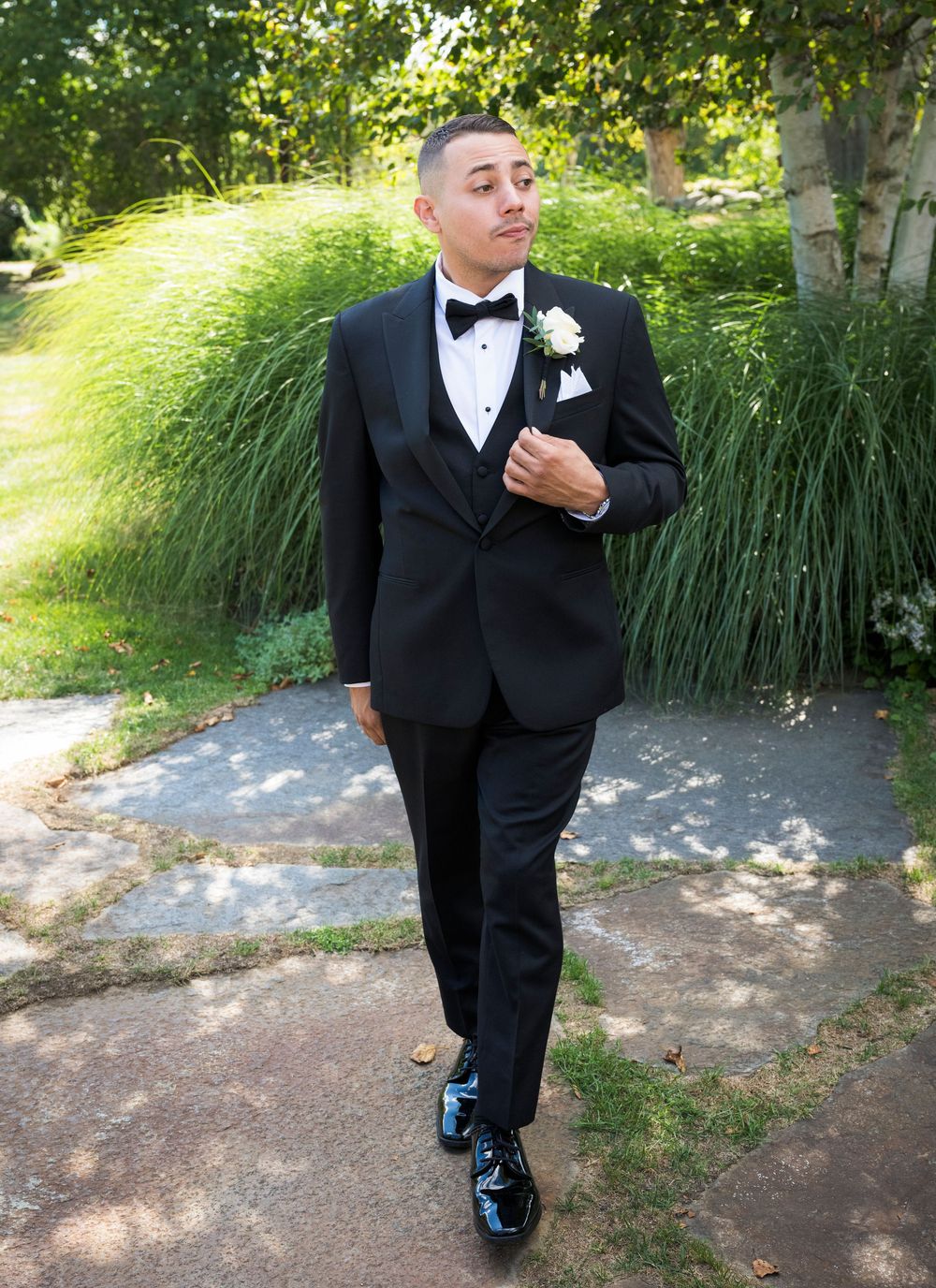 Formal wedding attire details showing black tuxedo and blue dress shoes outdoors.