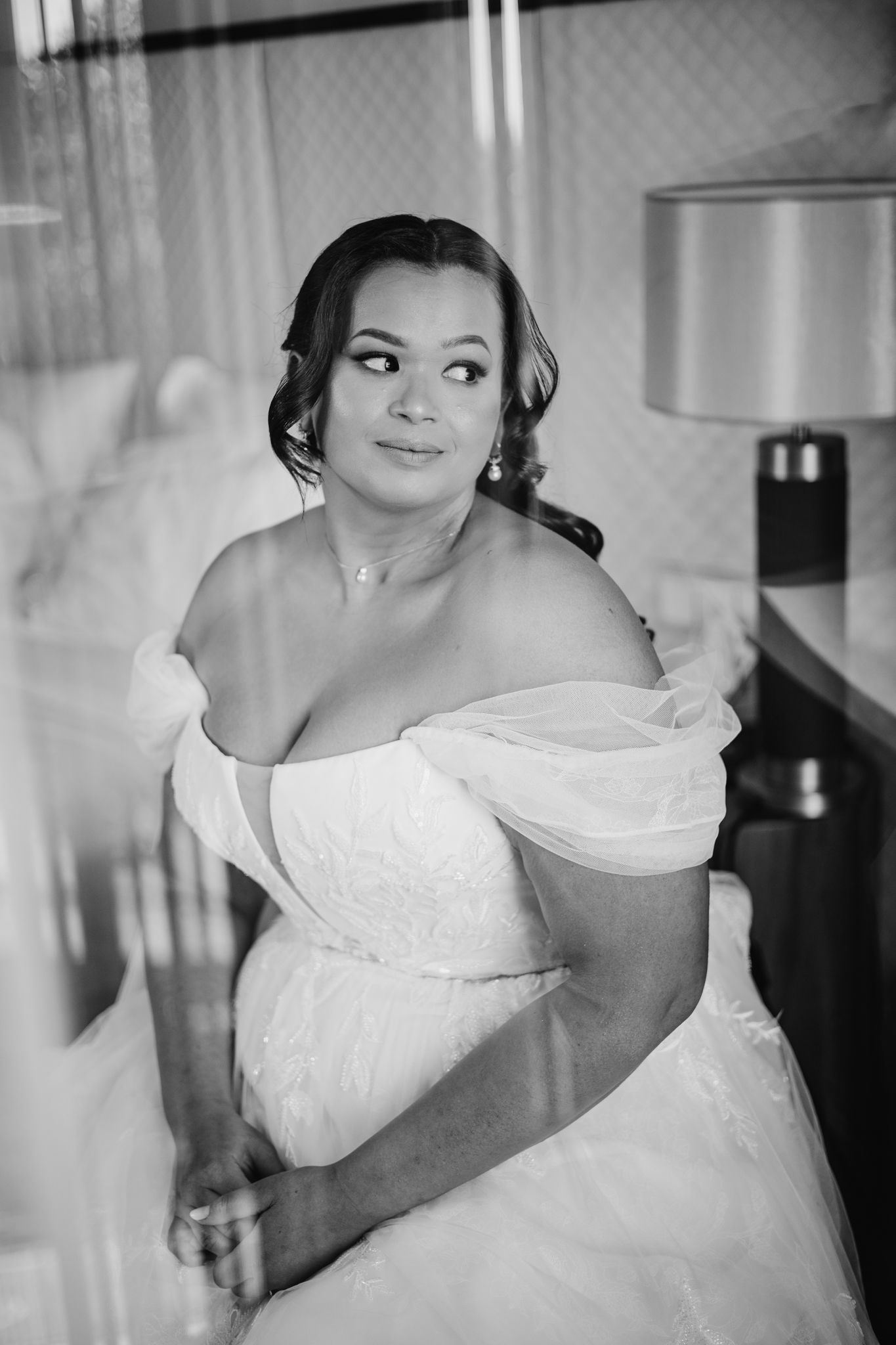 Black and white wedding photography series showing a bride in an elegant off-shoulder white gown in various poses.