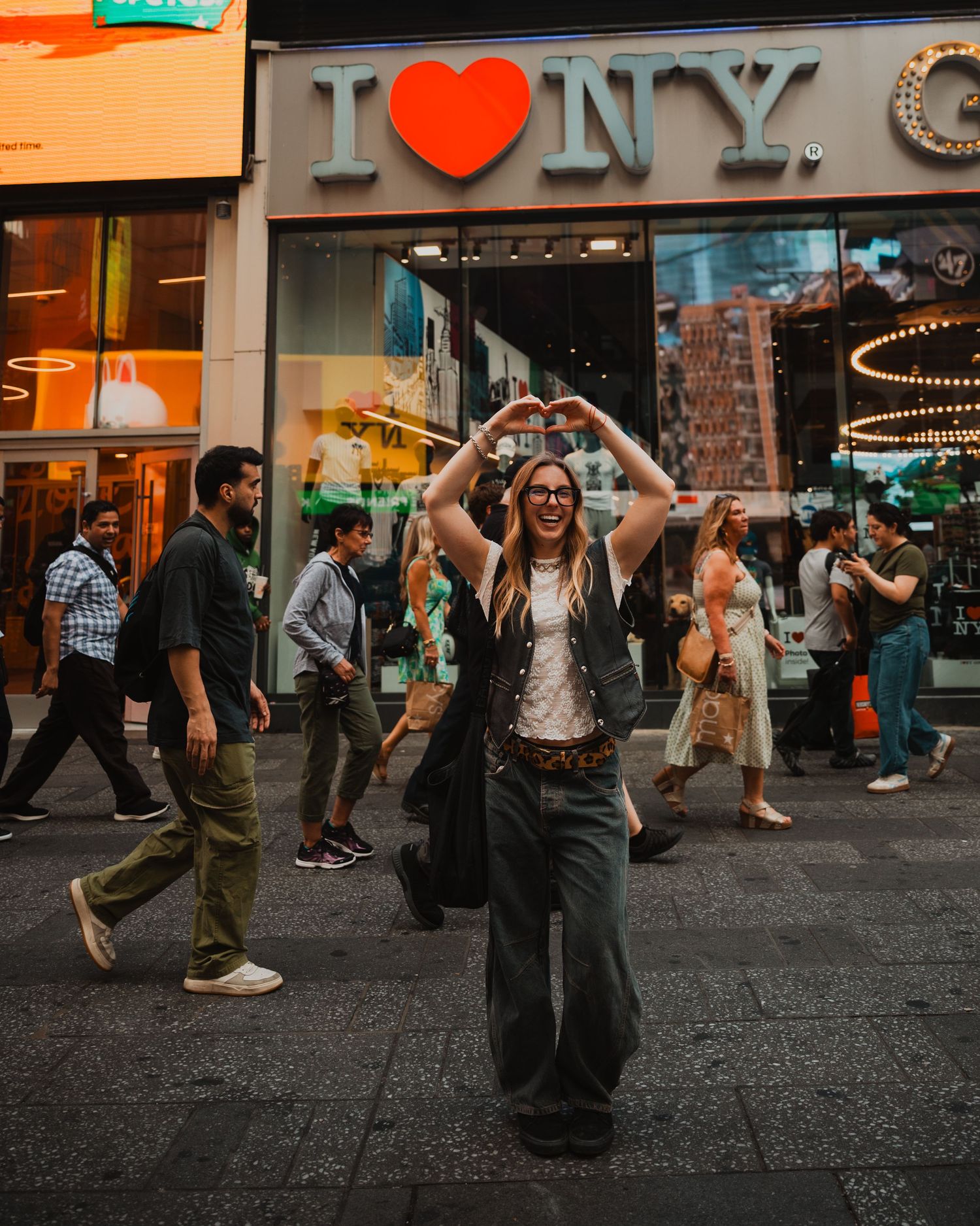 Street dancers performing energetic swing dance moves on a cobblestone sidewalk at dusk outside illuminated storefronts.