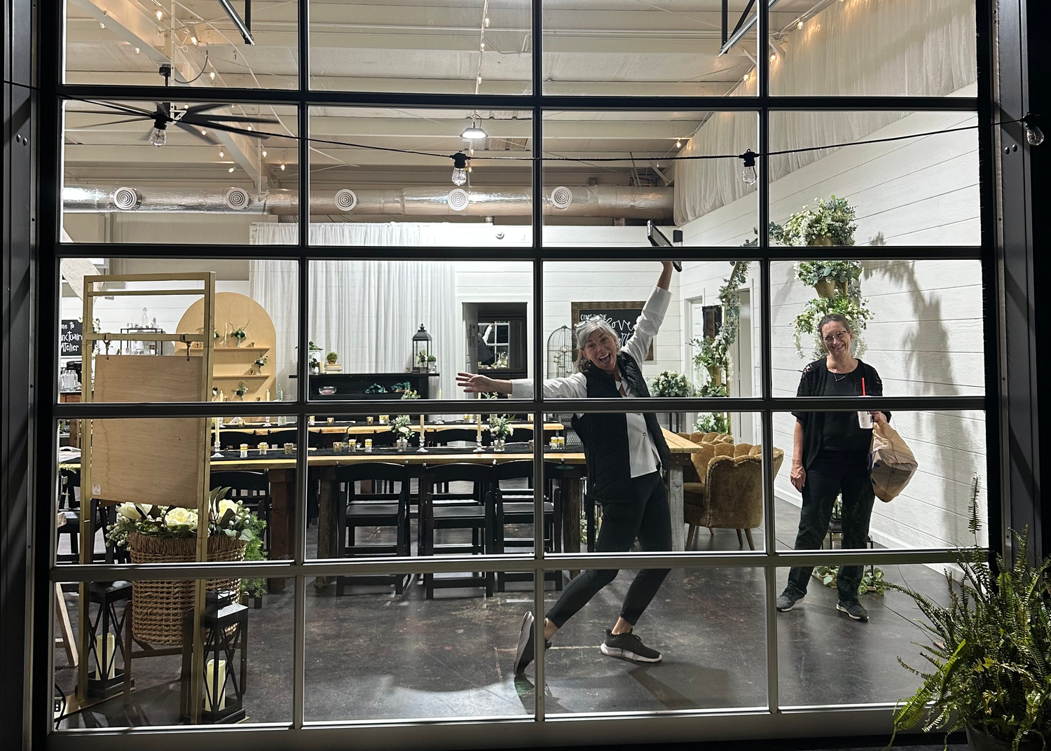 Large glass garage door with a wedding venue and a woman jumping on the other side