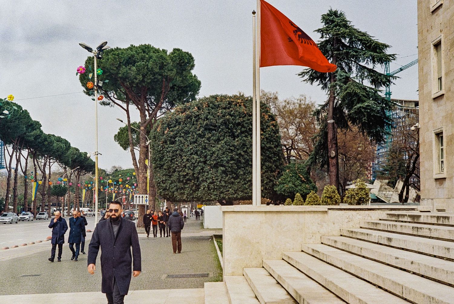 A vibrant street scene in Tirana, Albania, featuring colorful buildings, Skanderbeg Square, and the Et'hem Bey Mosque.