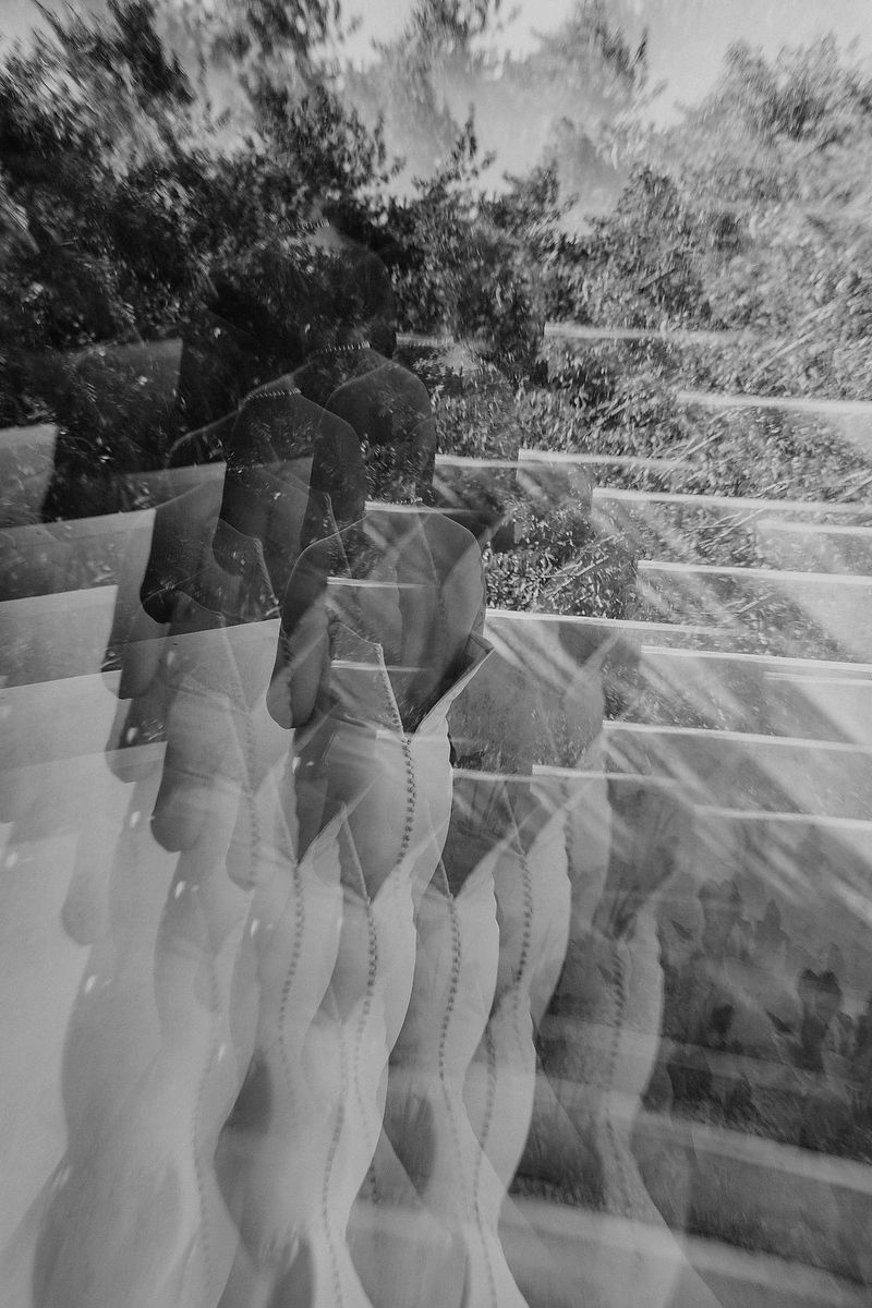 Abstract black and white double exposure of a person reflected through glass with trees in the background.