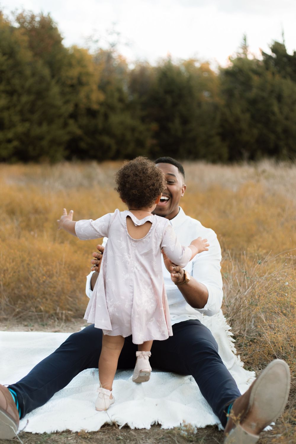 A joyful moment shared between parent and child sitting on a white blanket outdoors.