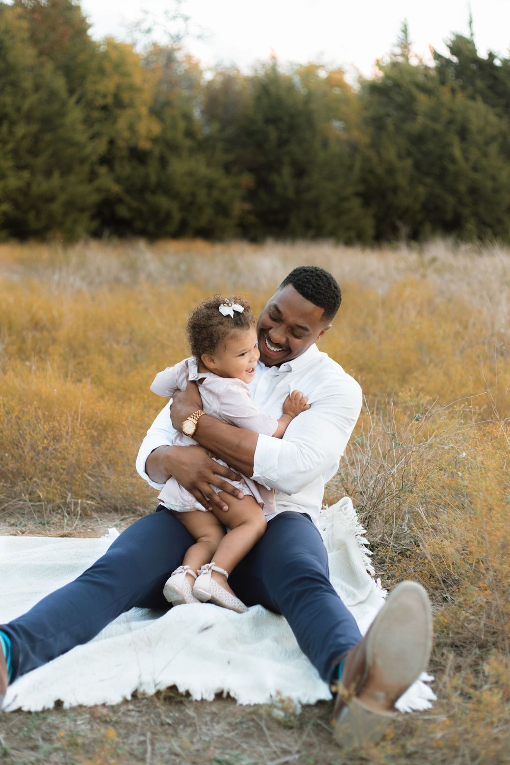 A heartwarming outdoor photo showing tender bonding moments between a parent and child sitting on a white blanket.