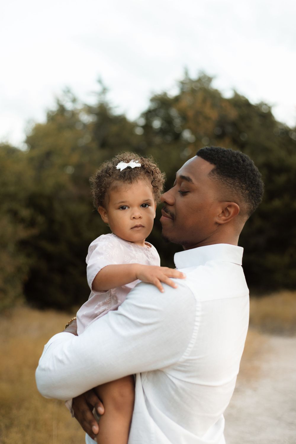 A touching moment captured between a parent and small child against a background of autumn trees.