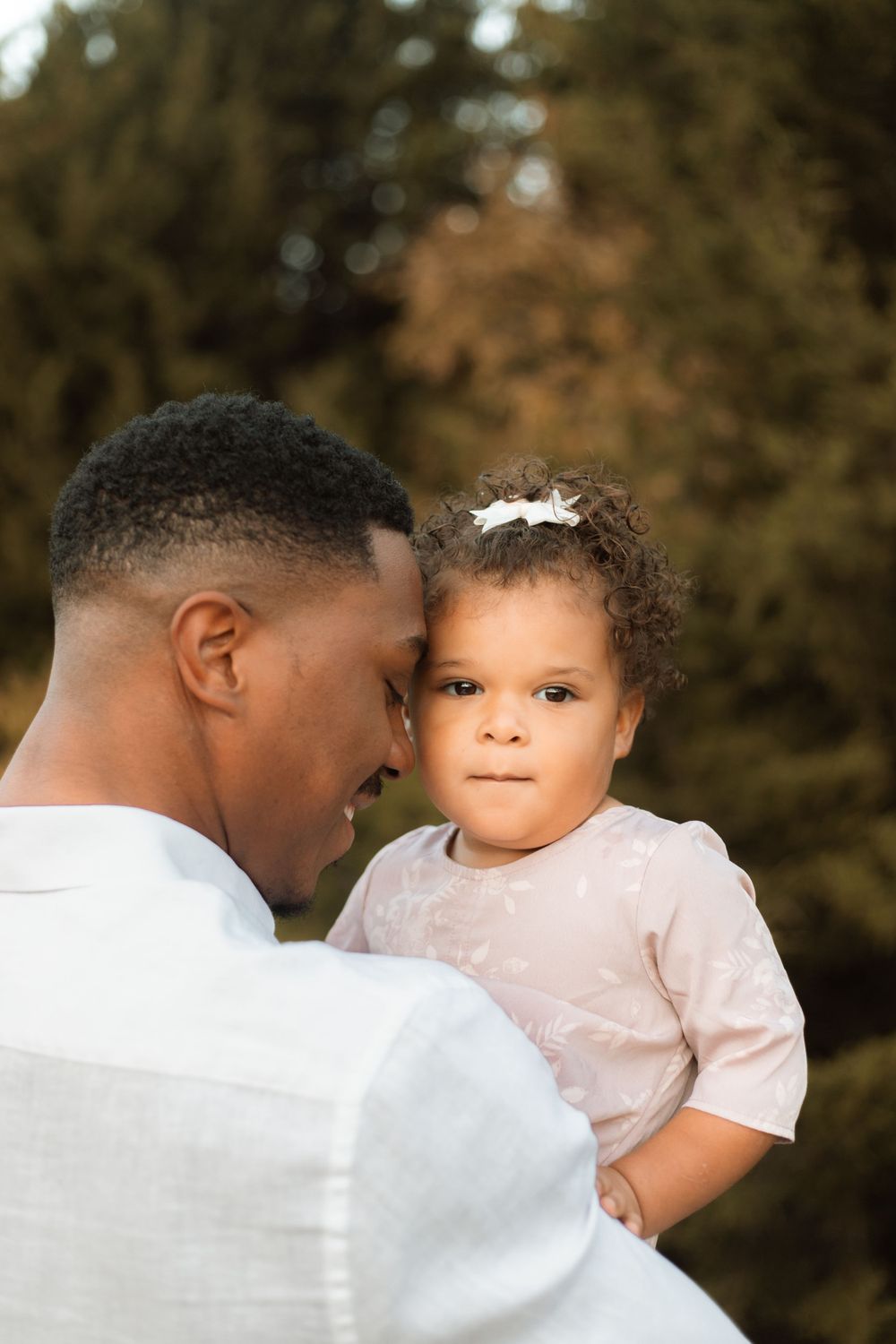An intimate close-up portrait showing a sweet moment between parent and child outdoors.