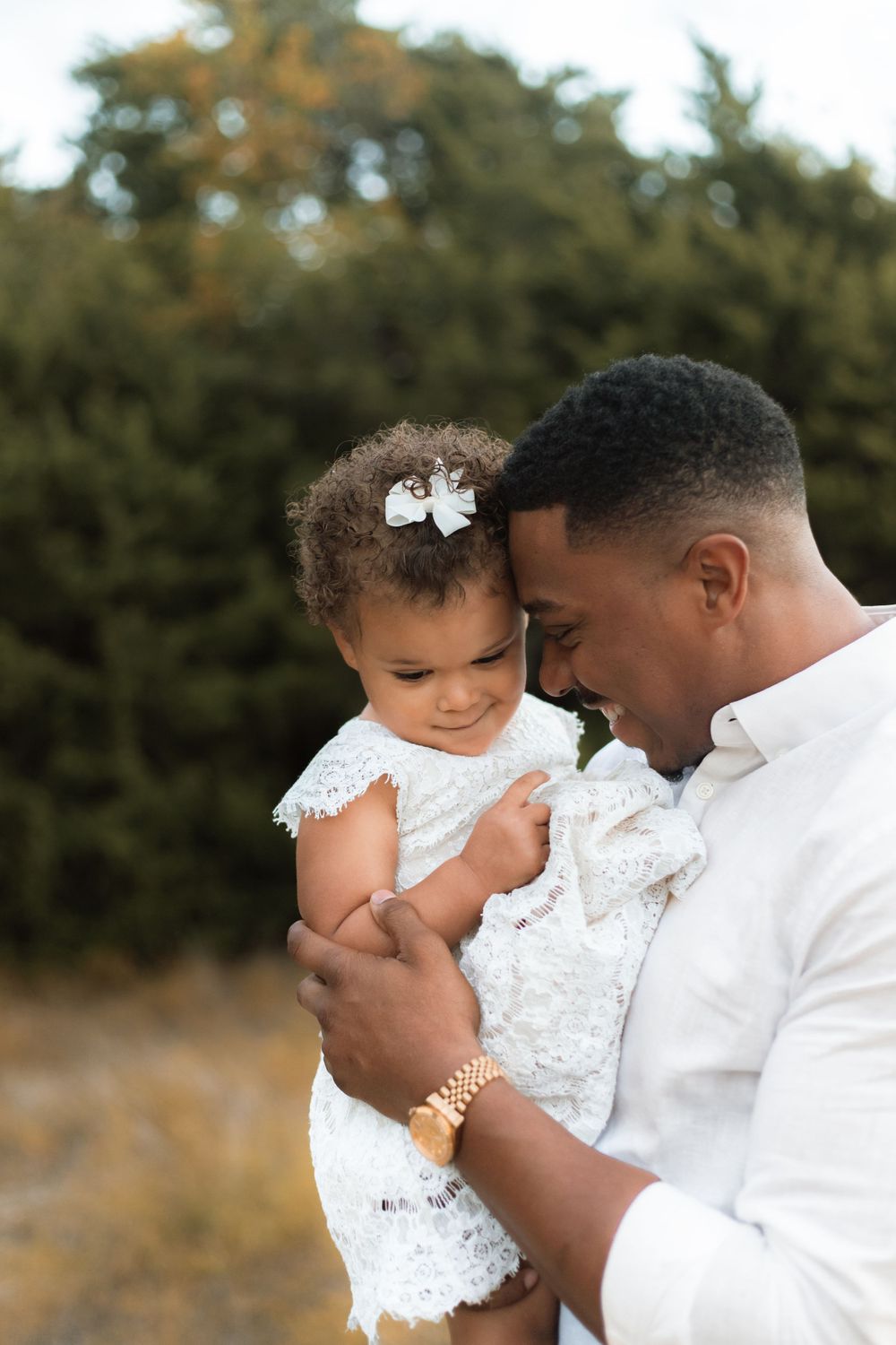 Intimate outdoor portrait of an adult and toddler sharing a close moment.