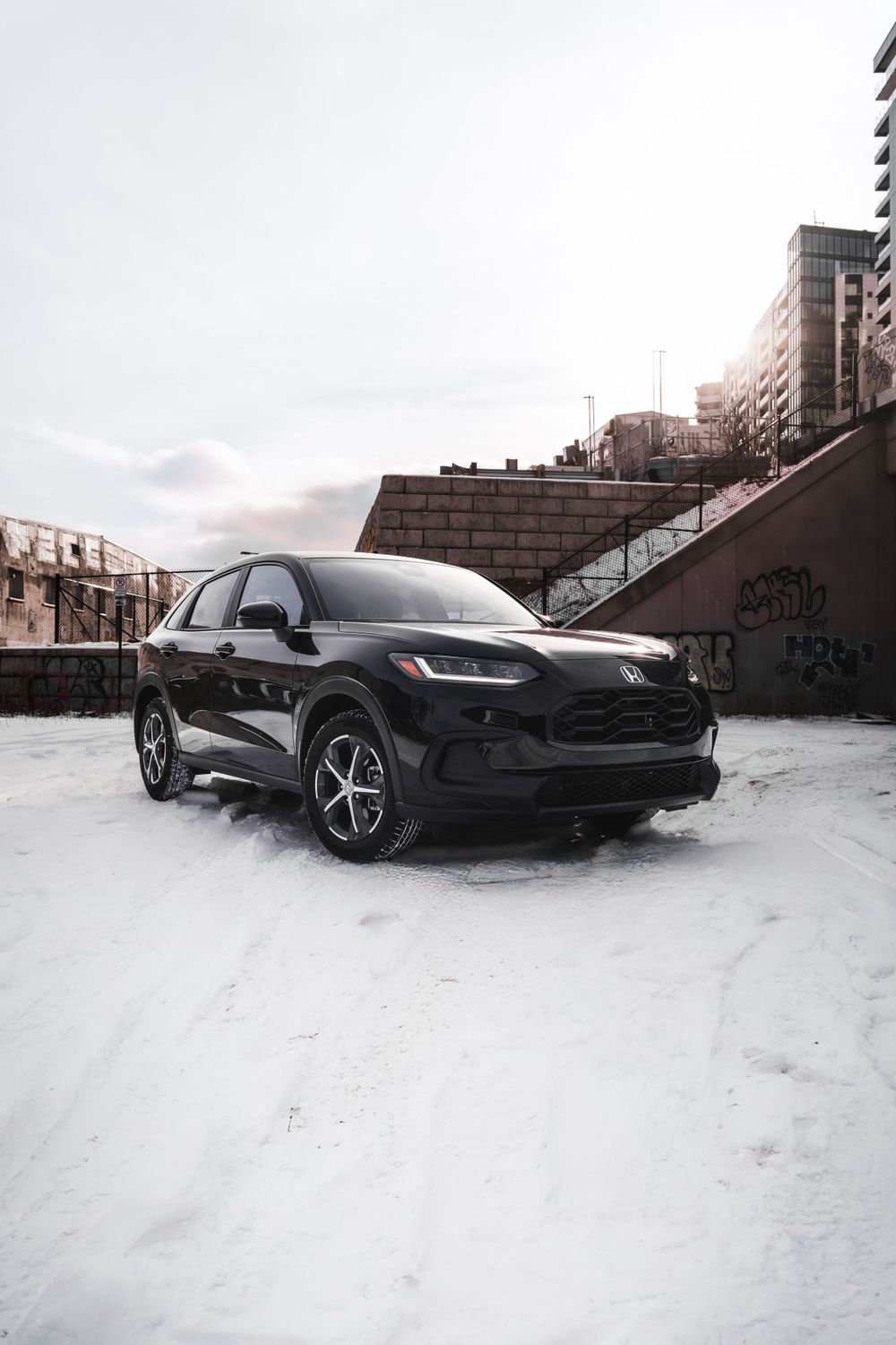 Black Honda HR-V SUV parked in snowy urban setting with buildings in background. Mtlshutter photography