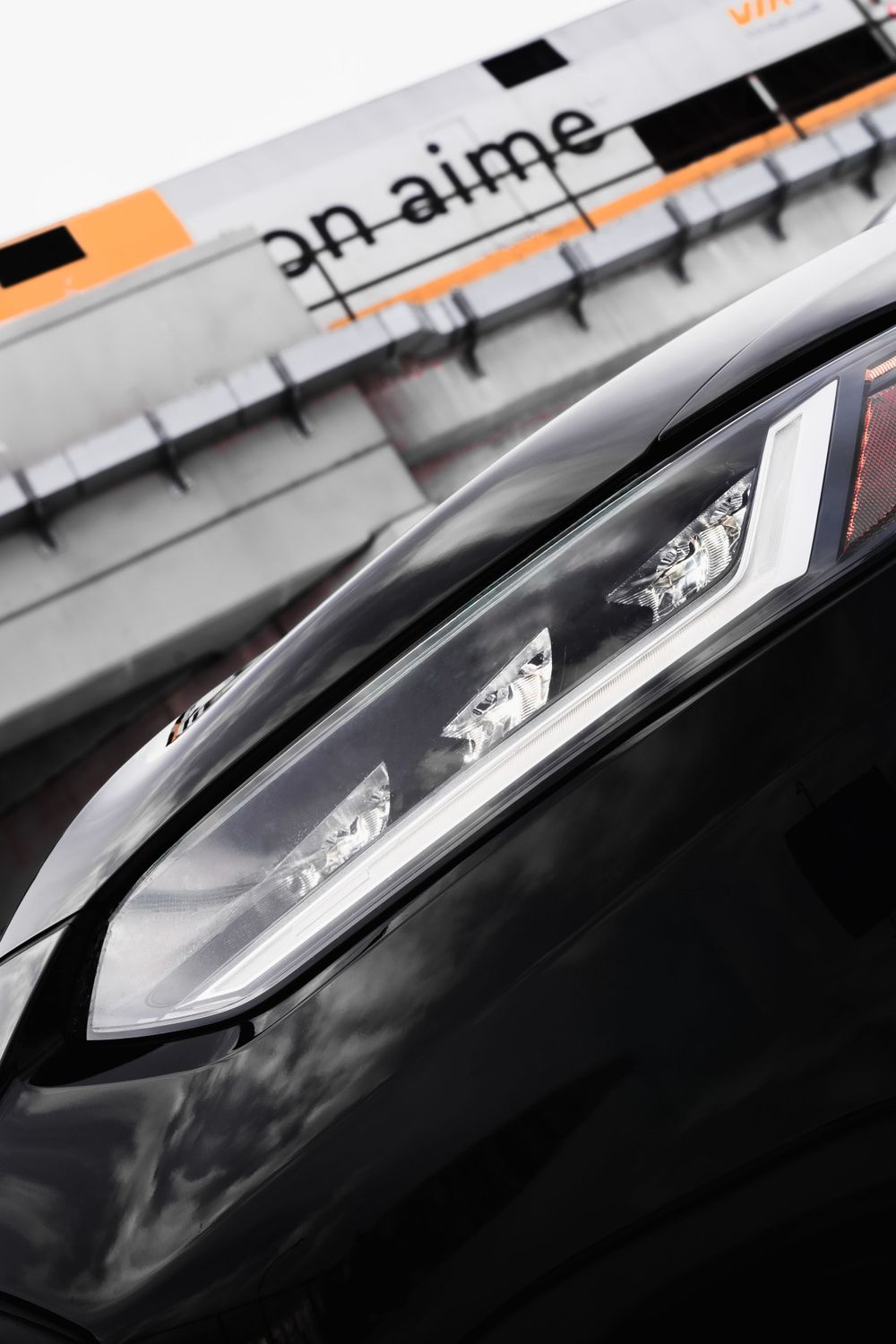 Detailed view of sleek LED headlight design against a black car exterior. Mtlshutter photography