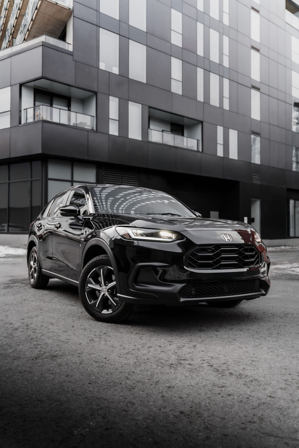 Black SUV parked in front of modern gray building with geometric architecture.Mtlshutter photography
