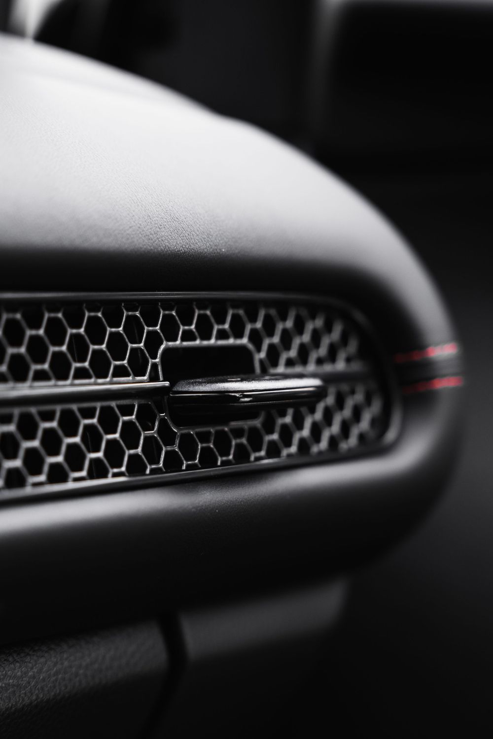 Detail shot of honeycomb grille pattern with chrome accent on black car exterior.Mtlshutter photography