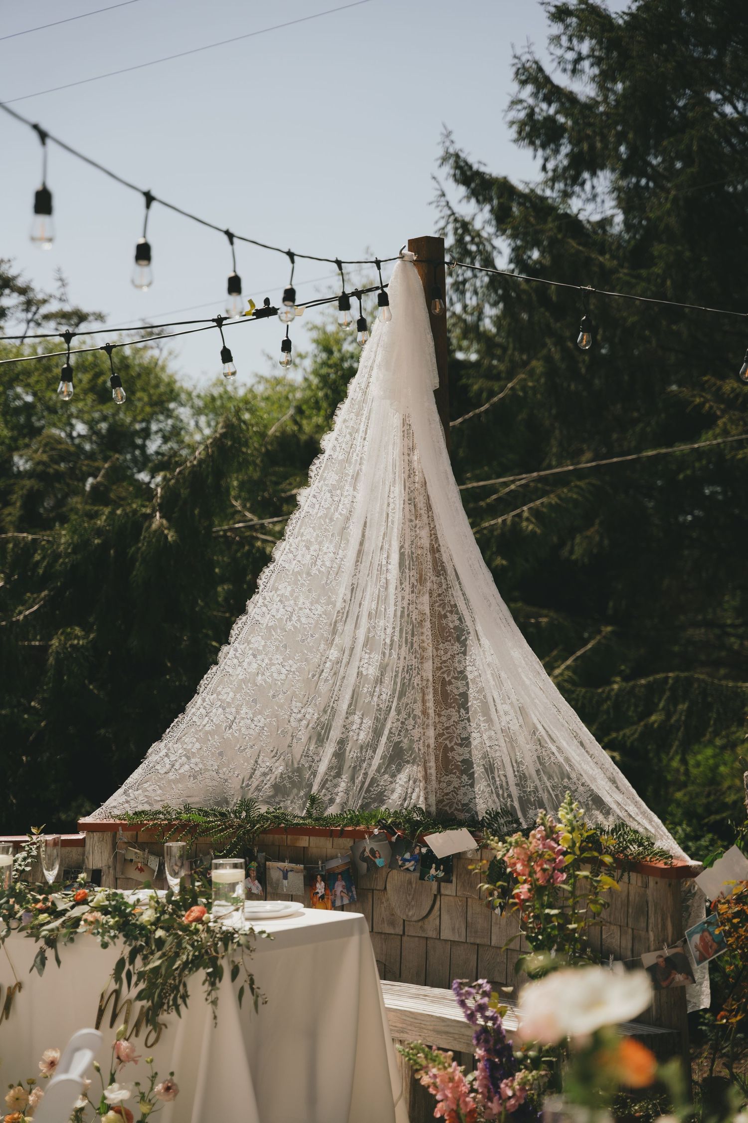 Crystal chandelier hanging above decorated tables with string lights creating an elegant outdoor setting. Oregon coast micro wedding