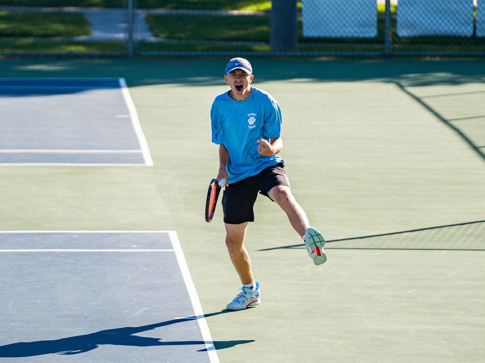 Tennis player in motion during match on sunny outdoor court.