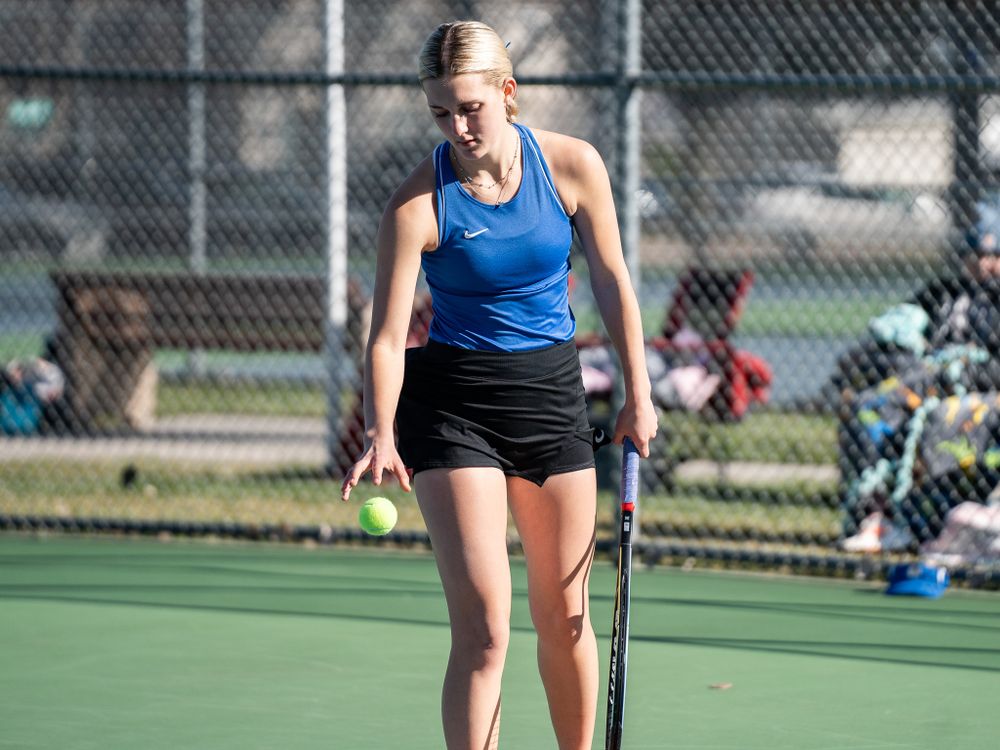 Tennis player in blue tank top stands with racquet on court.