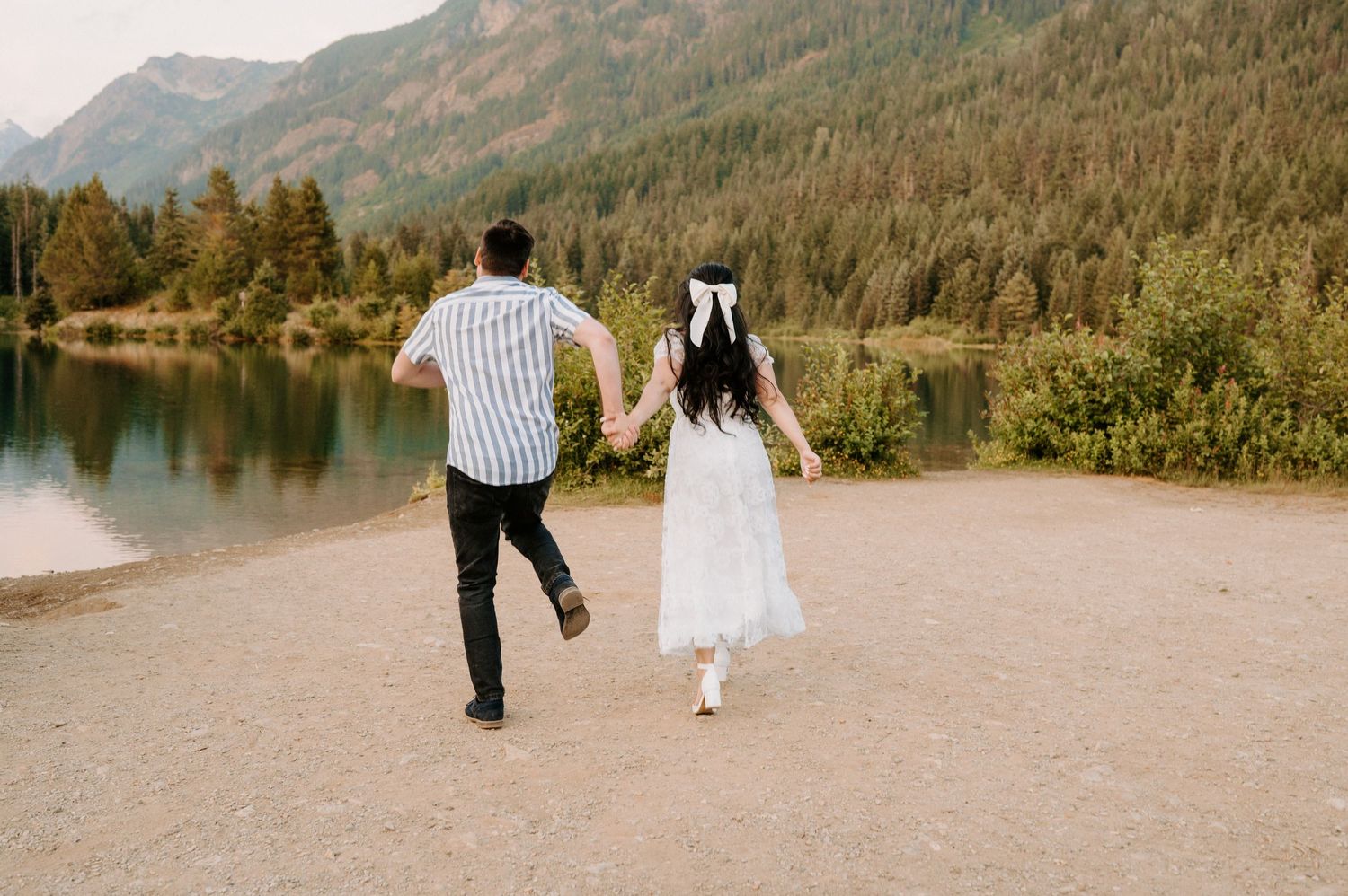 Couple walking hand in hand along a scenic mountain trail during their wedding day.