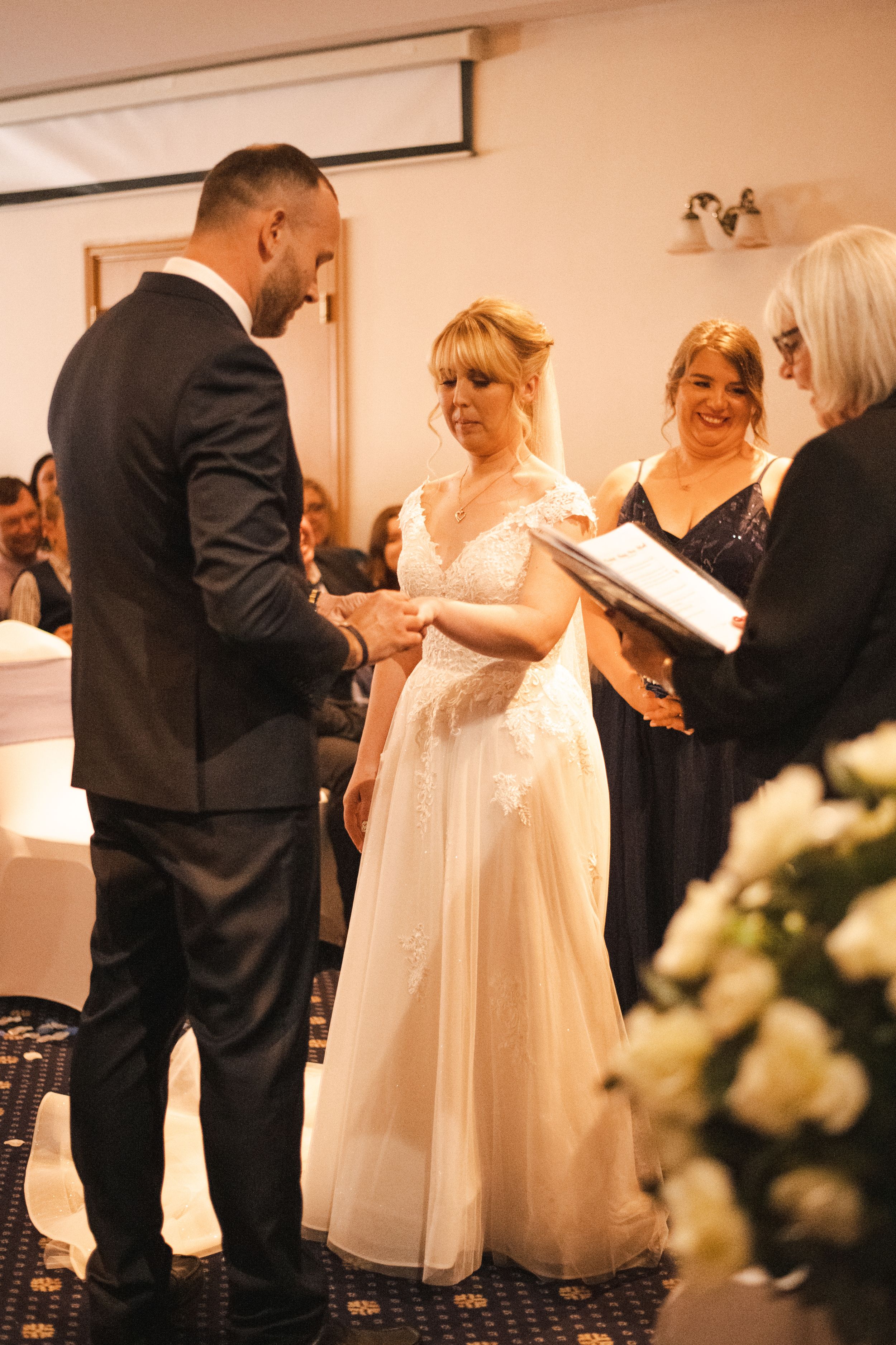 Wedding ceremony indoors with guests watching the couple exchange vows.