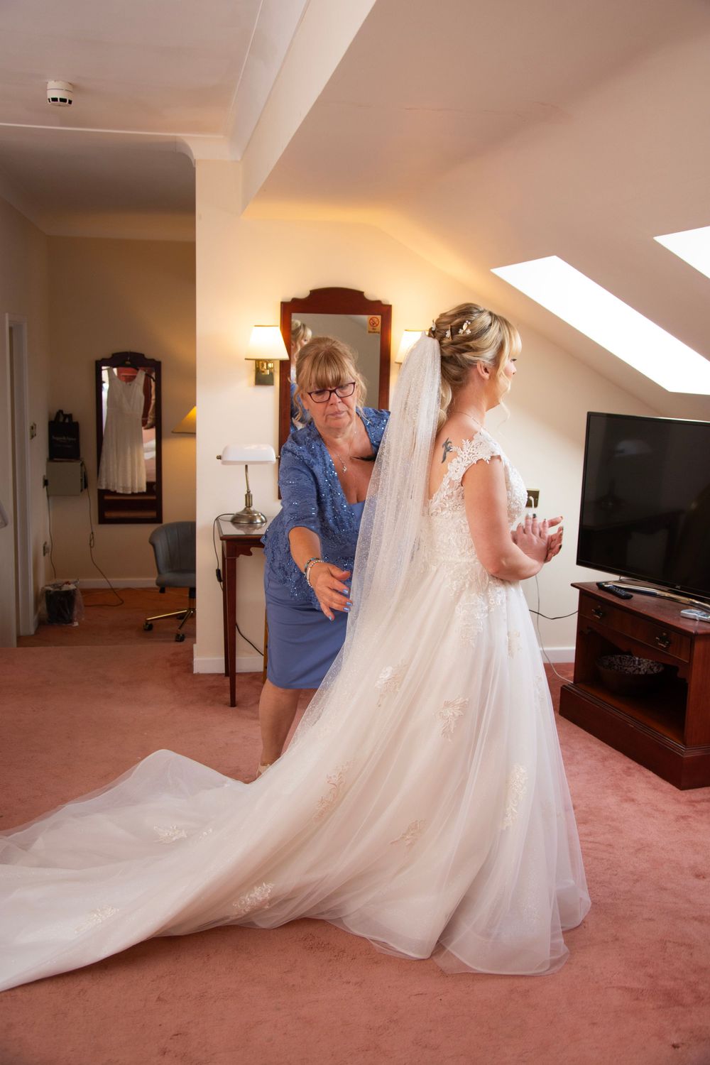 Wedding dress preparation in a hotel room with flowing white gown and veil.