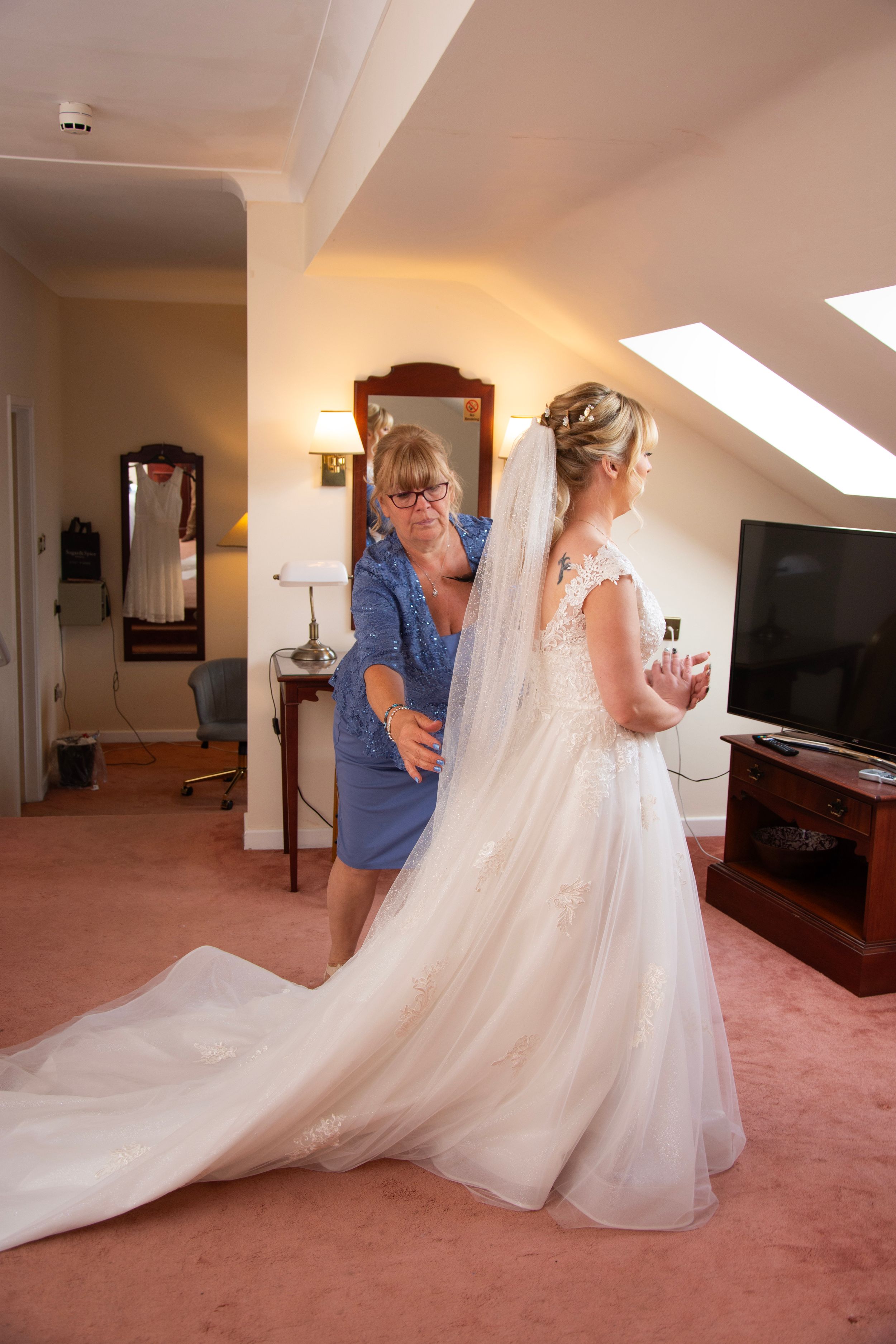 Wedding dress preparation in a hotel room with flowing white gown and veil.